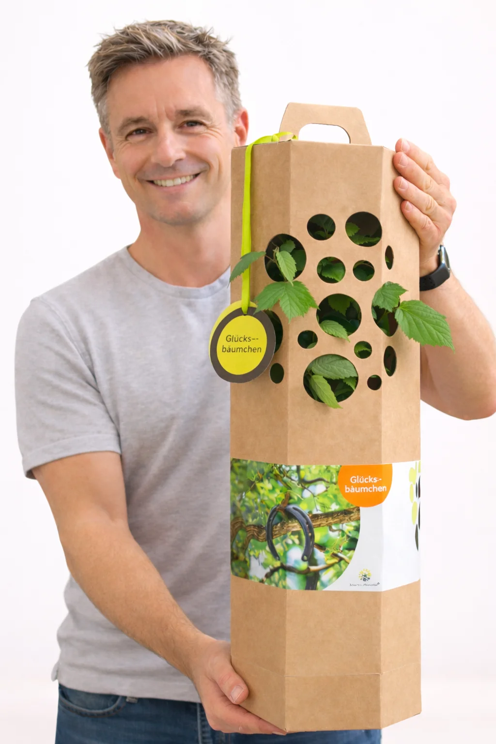 Mann hält einen Glücksbaum als Geschenk in Geschenkverpackung mit Glückwunschkarte