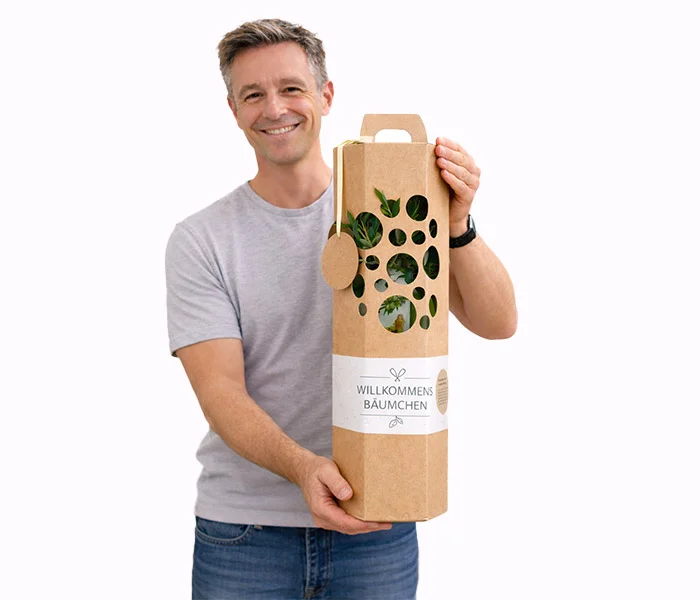 Mann hält Willkommensgeschenk für neue Mitarbeiter – Baum in Geschenkverpackung